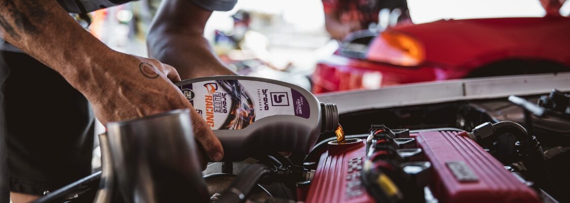 man pouring brava elite racing oil into a car